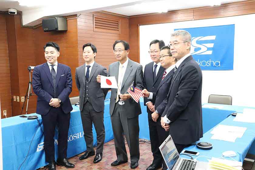 At the signing ceremony, President Masayoshi Ito held flags on center with his subordinates and consultants of Nihon M&A Center.